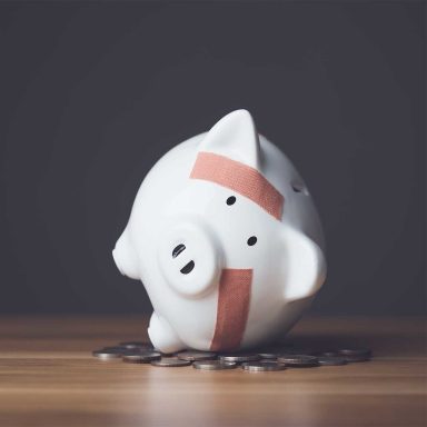 Financial problem, Bankrupt or fail in business concept. White piggy bank with plastic adhesive bandages on wooden desk with dark copy space wall background.