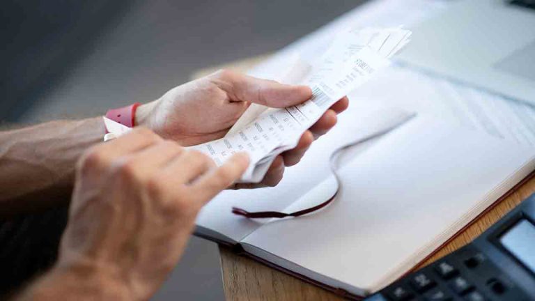 Close up of businessman holding bills while studying expenses