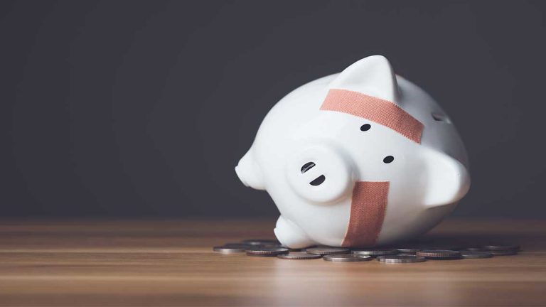 Financial problem, Bankrupt or fail in business concept. White piggy bank with plastic adhesive bandages on wooden desk with dark copy space wall background.