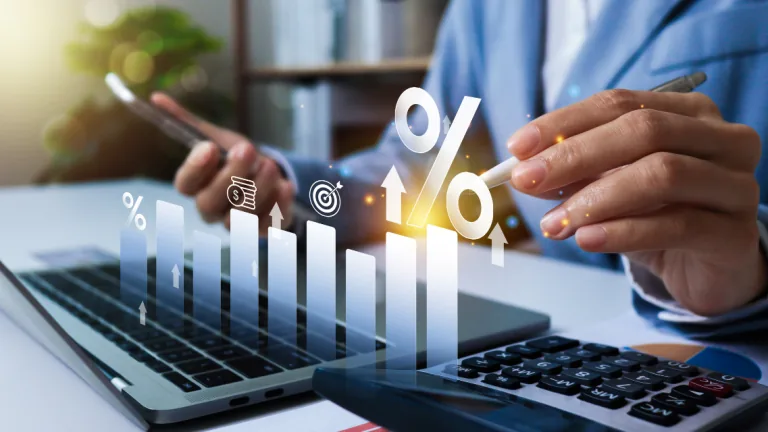 A small business owner looking at his computer and phone reviewing financial data.